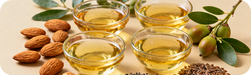 Almonds and seeds beside small dishes of oil